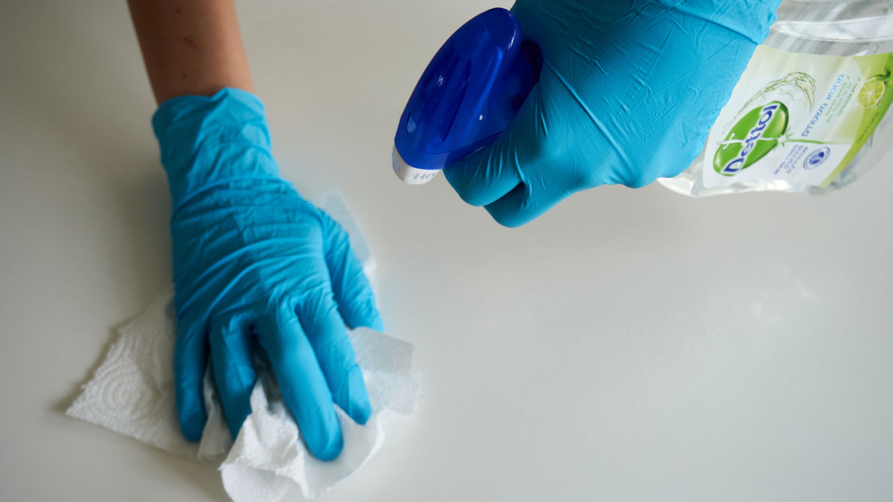 Behandschuhte Hände reinigen eine Oberfläche – Grundreinigung
